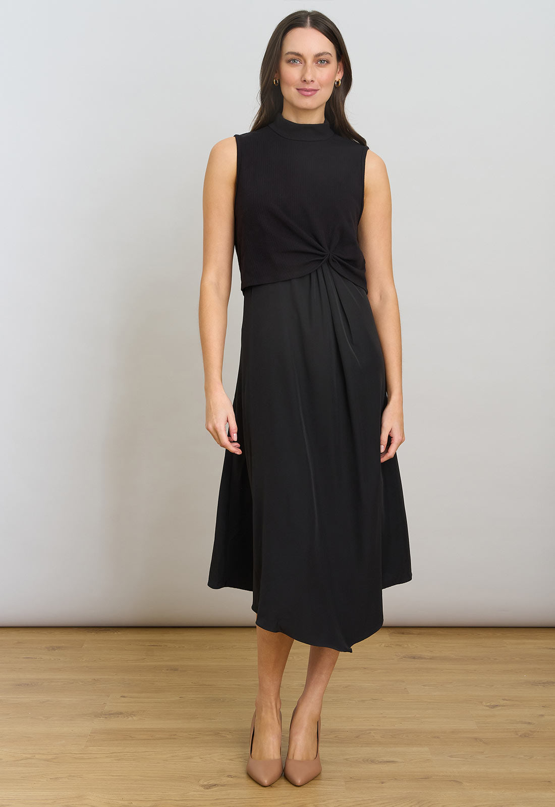 Woman wearing a black sleeveless dress against a plain background