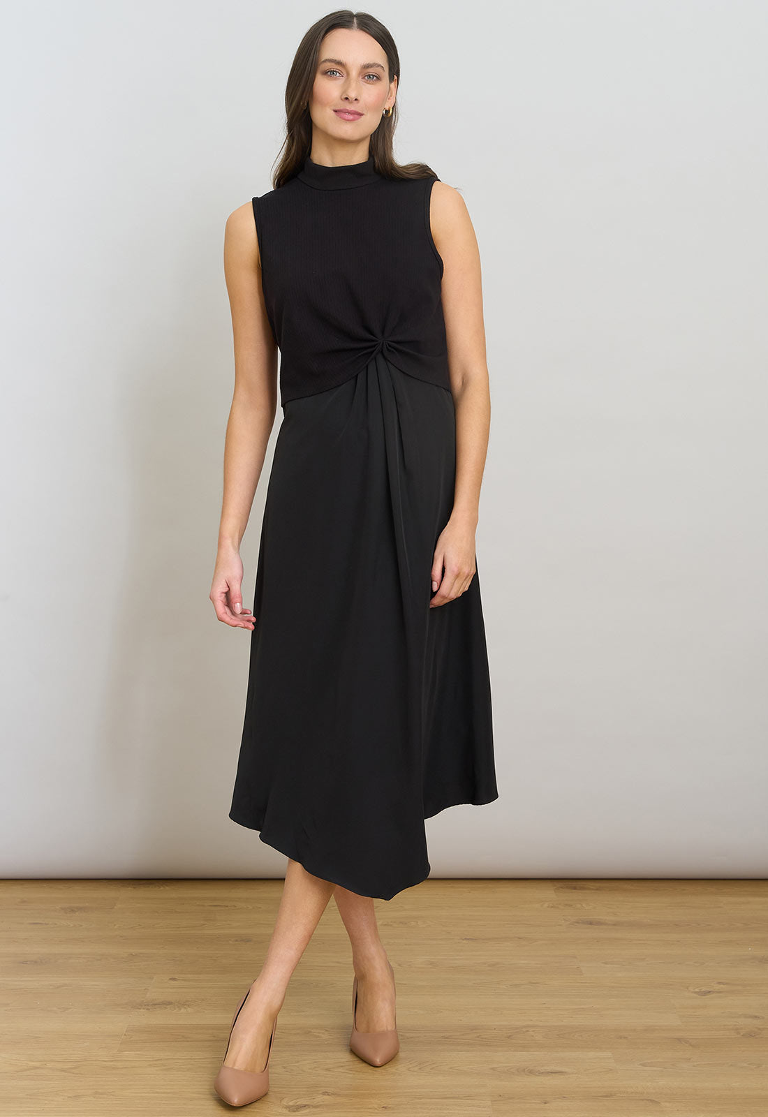 Woman wearing a black sleeveless dress against a plain background