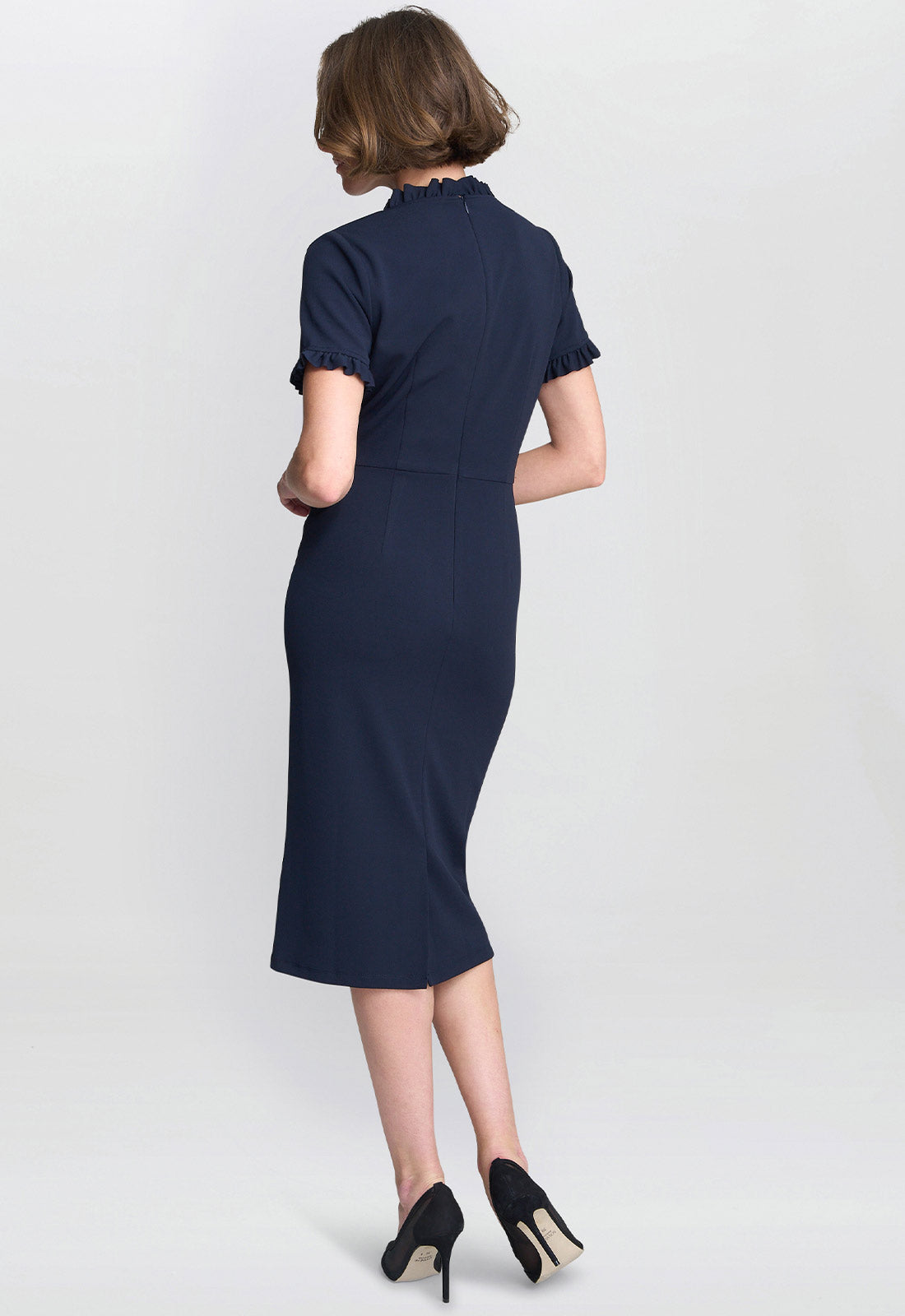Woman wearing a navy blue dress on a light gray background