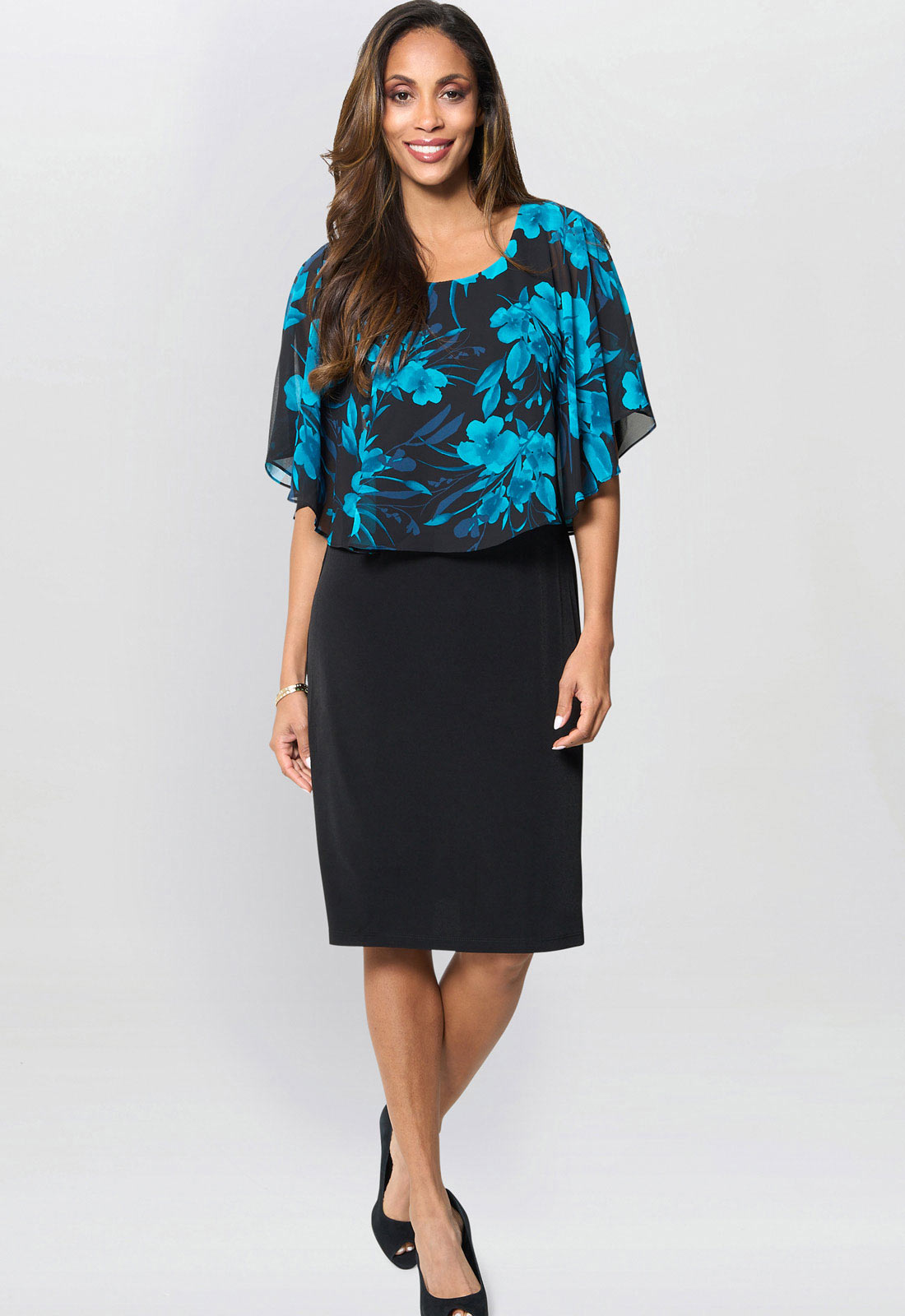 Woman wearing a black and blue floral top with a black skirt on a white background