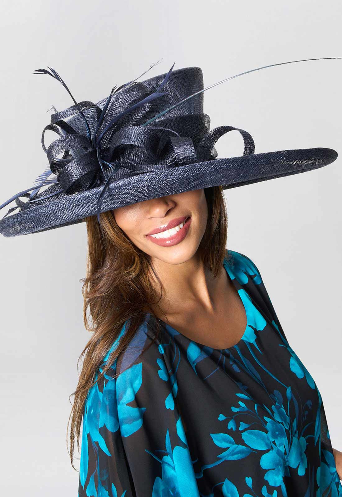 Woman wearing a large navy blue hat with decorative elements on a white background