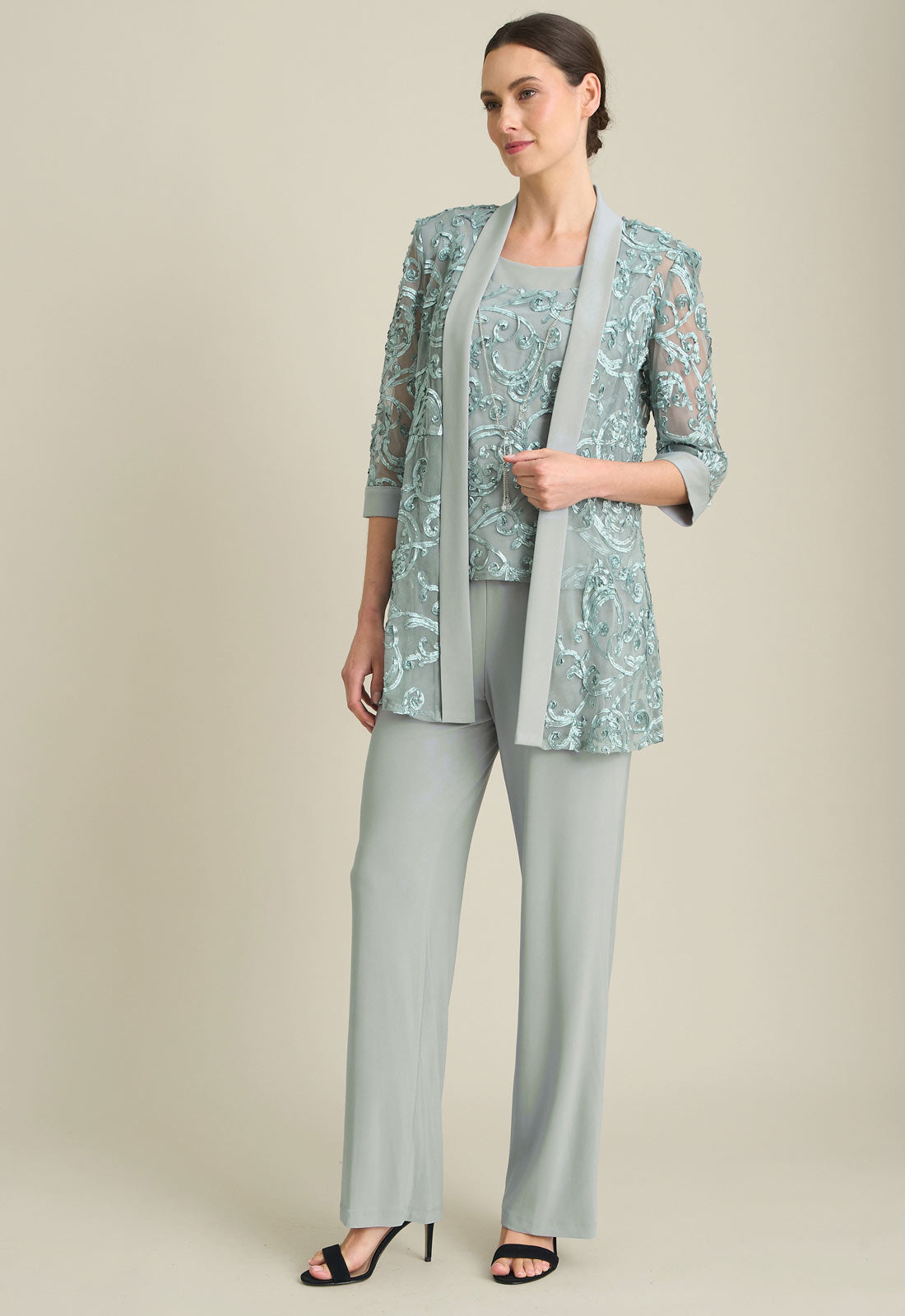 Woman wearing a light blue floral jacket with matching pants on a beige background