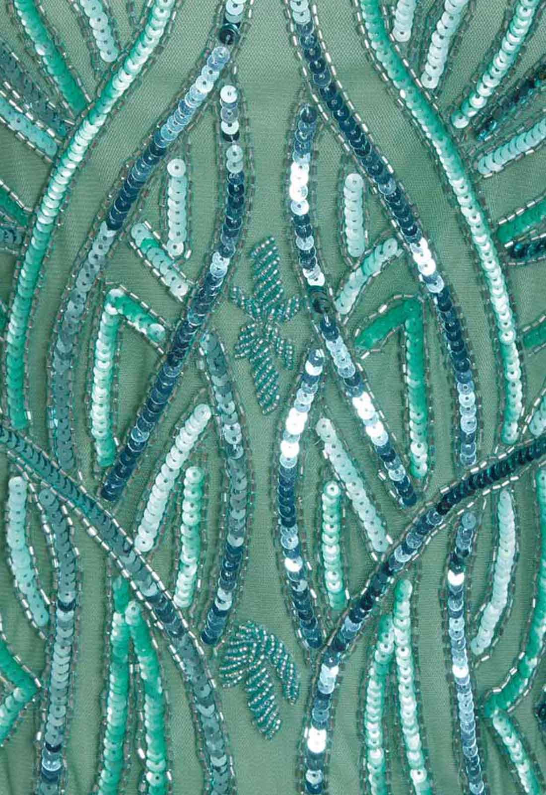 Close-up of a fabric with green and blue bead pattern on a green background