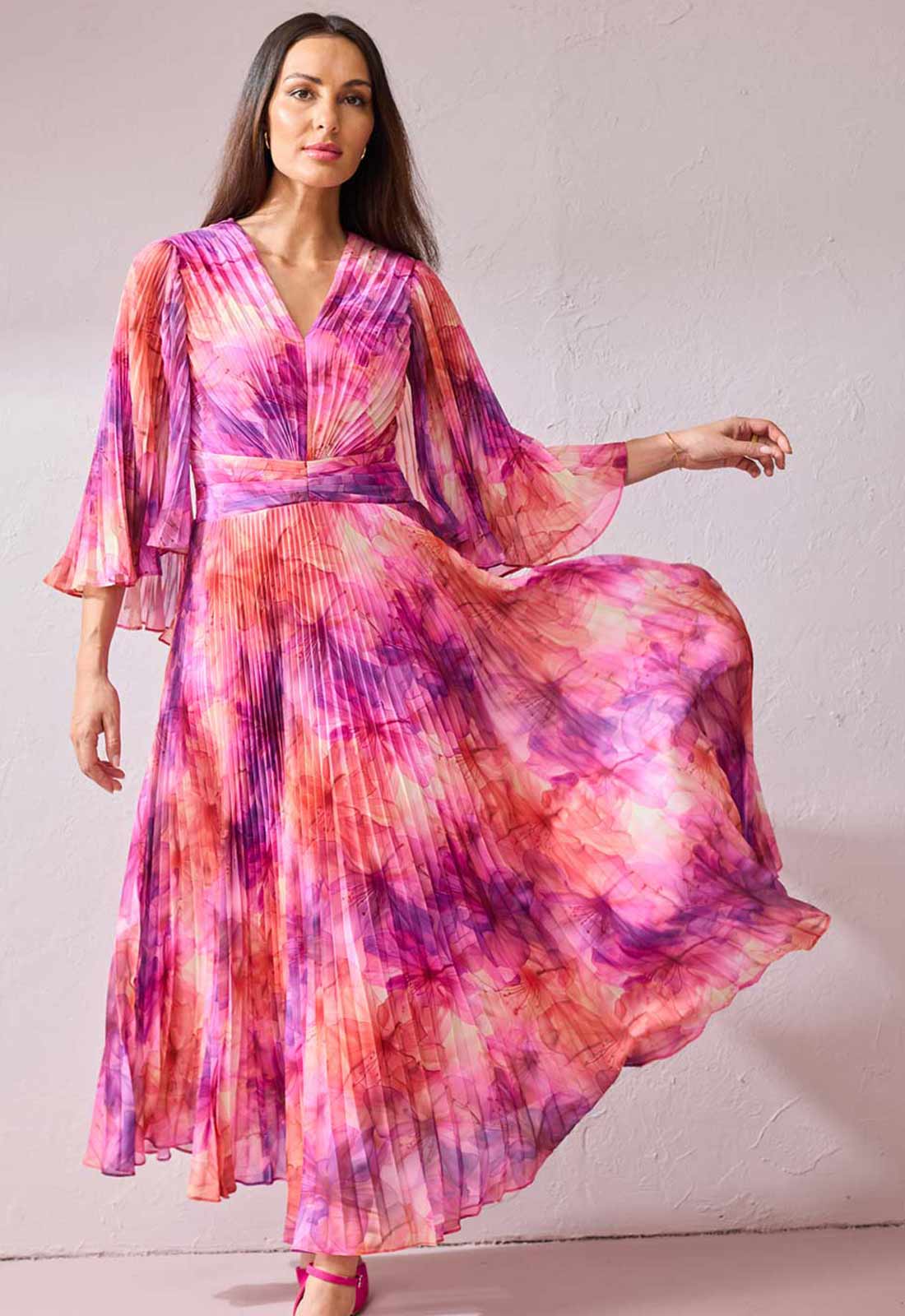 Woman wearing a colorful tie-dye dress against a plain background