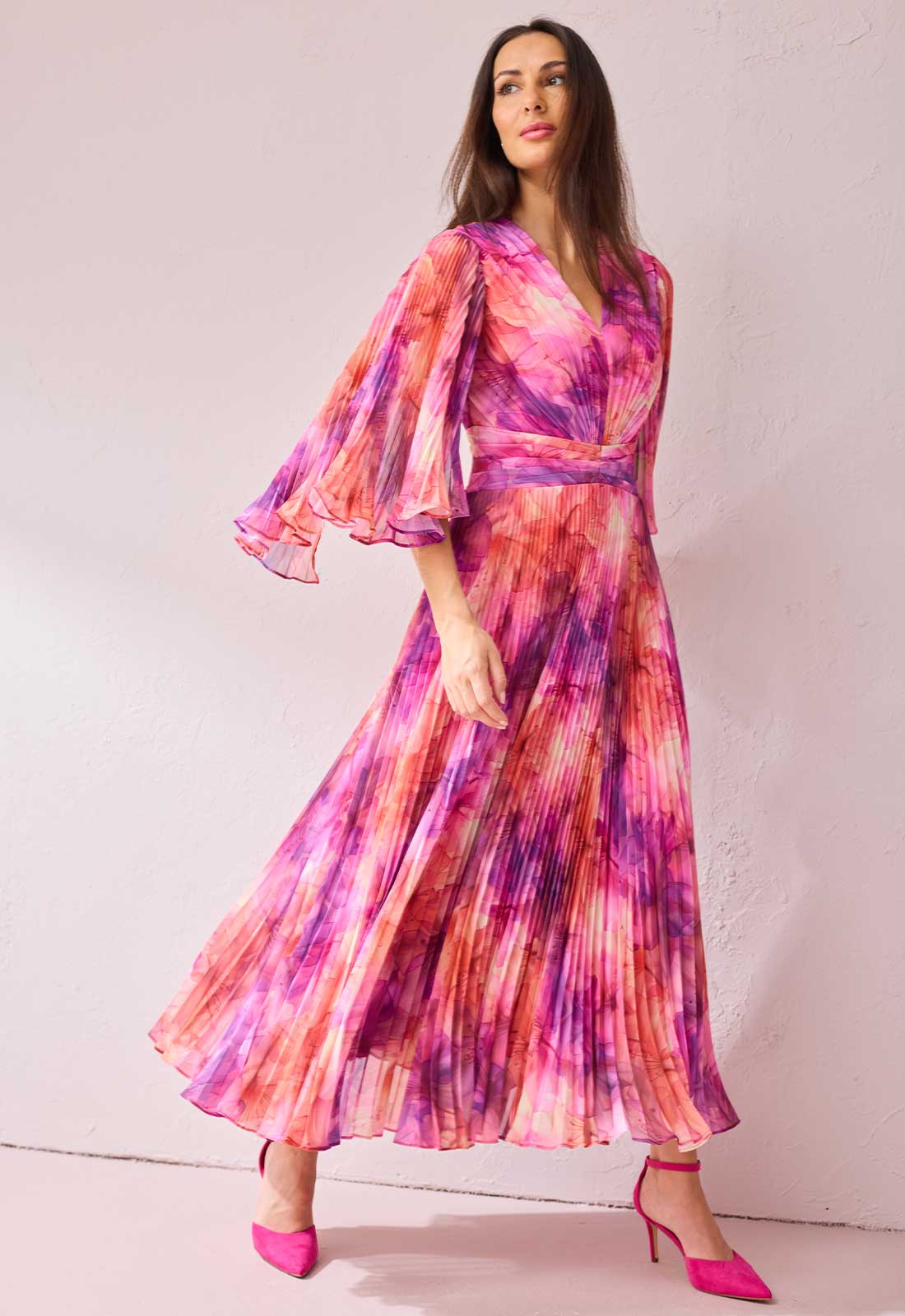 Woman wearing a colorful dress with bell sleeves against a white background