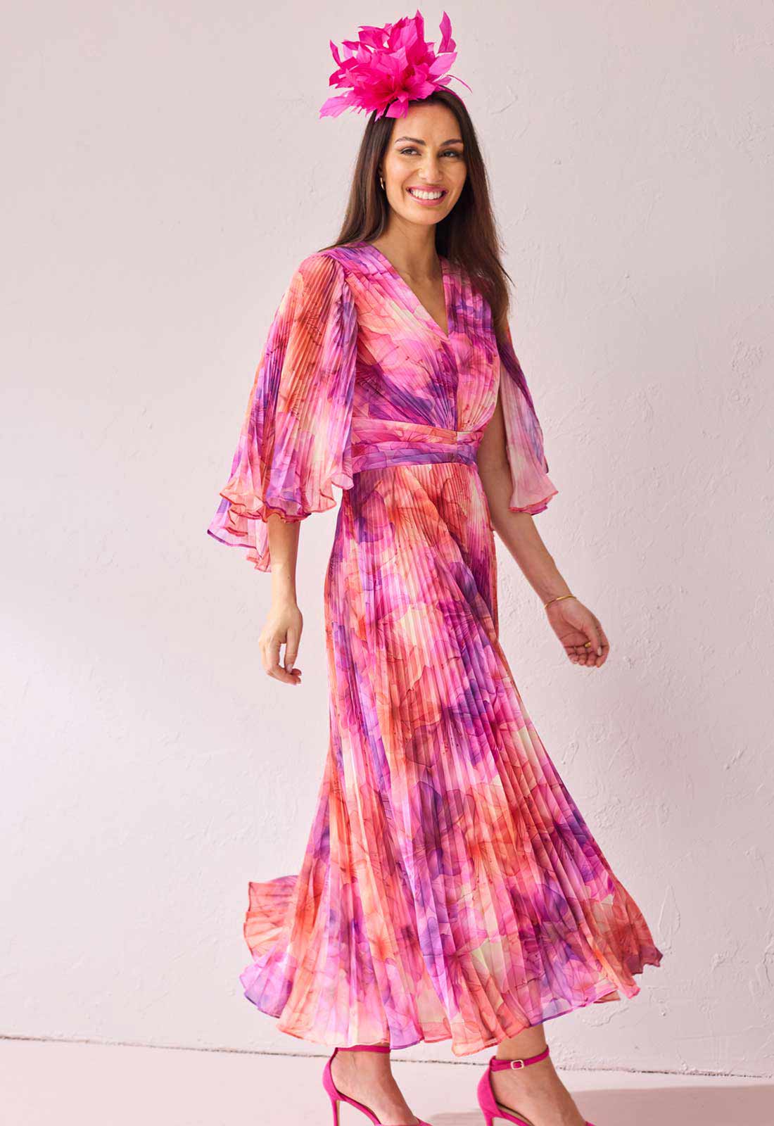 Woman wearing a colorful dress with a pink floral headpiece against a white background