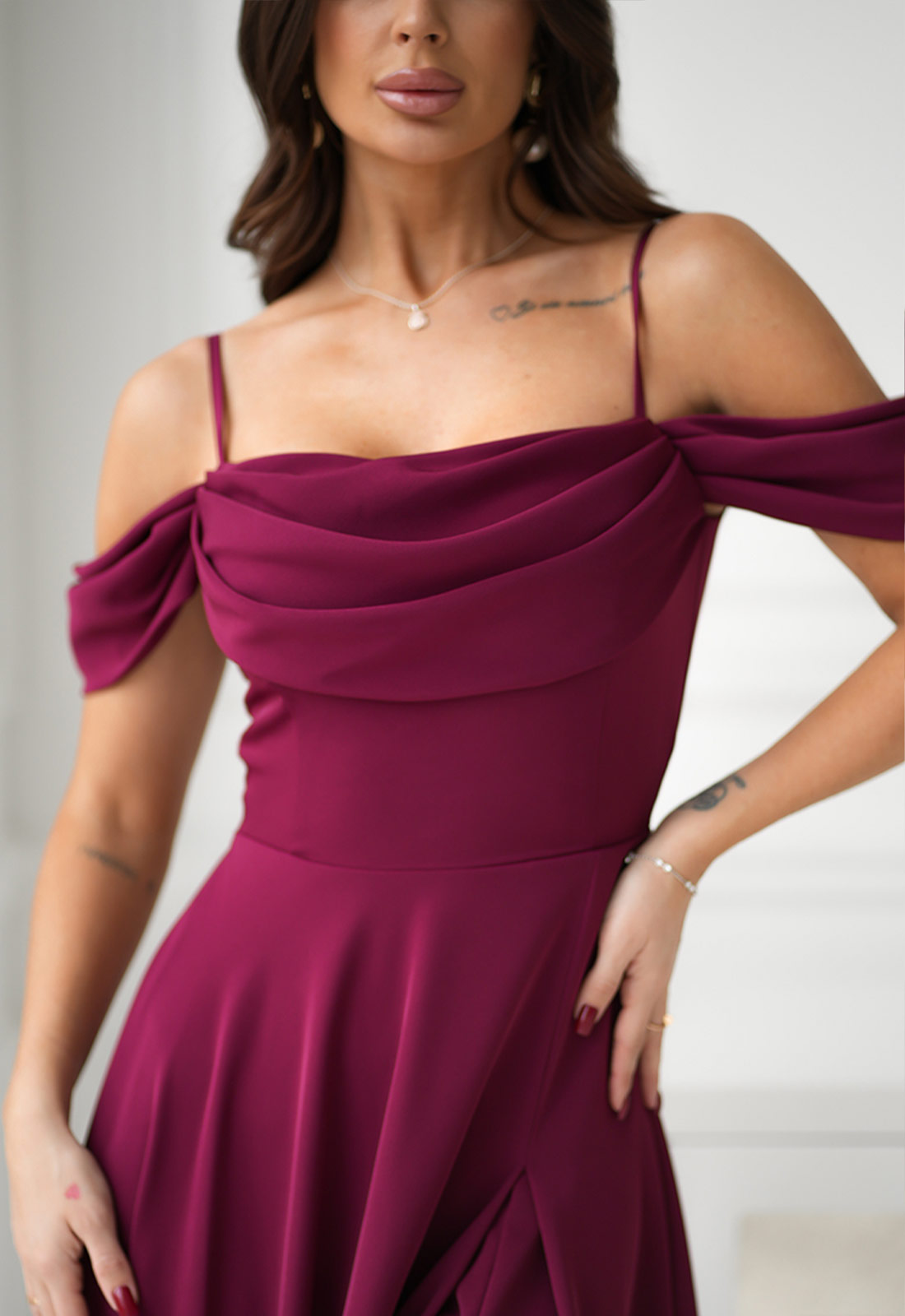 Woman wearing a burgundy off-shoulder dress against a neutral background