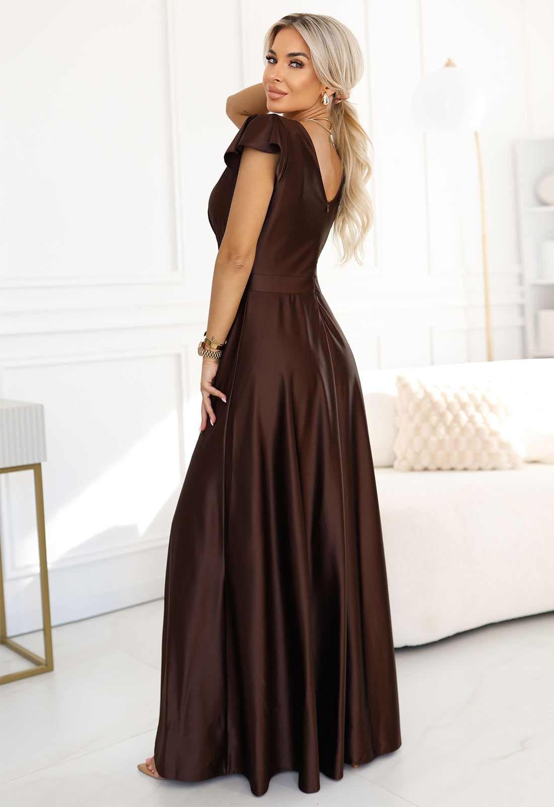 Woman wearing a brown evening gown in a bright room.