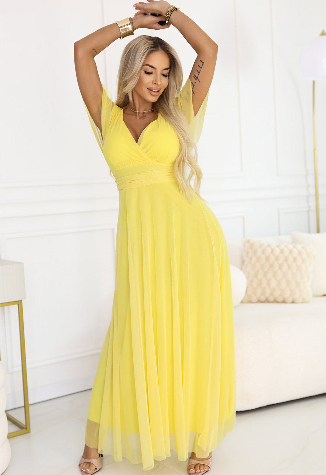 Woman in a yellow dress posing in a bright room.