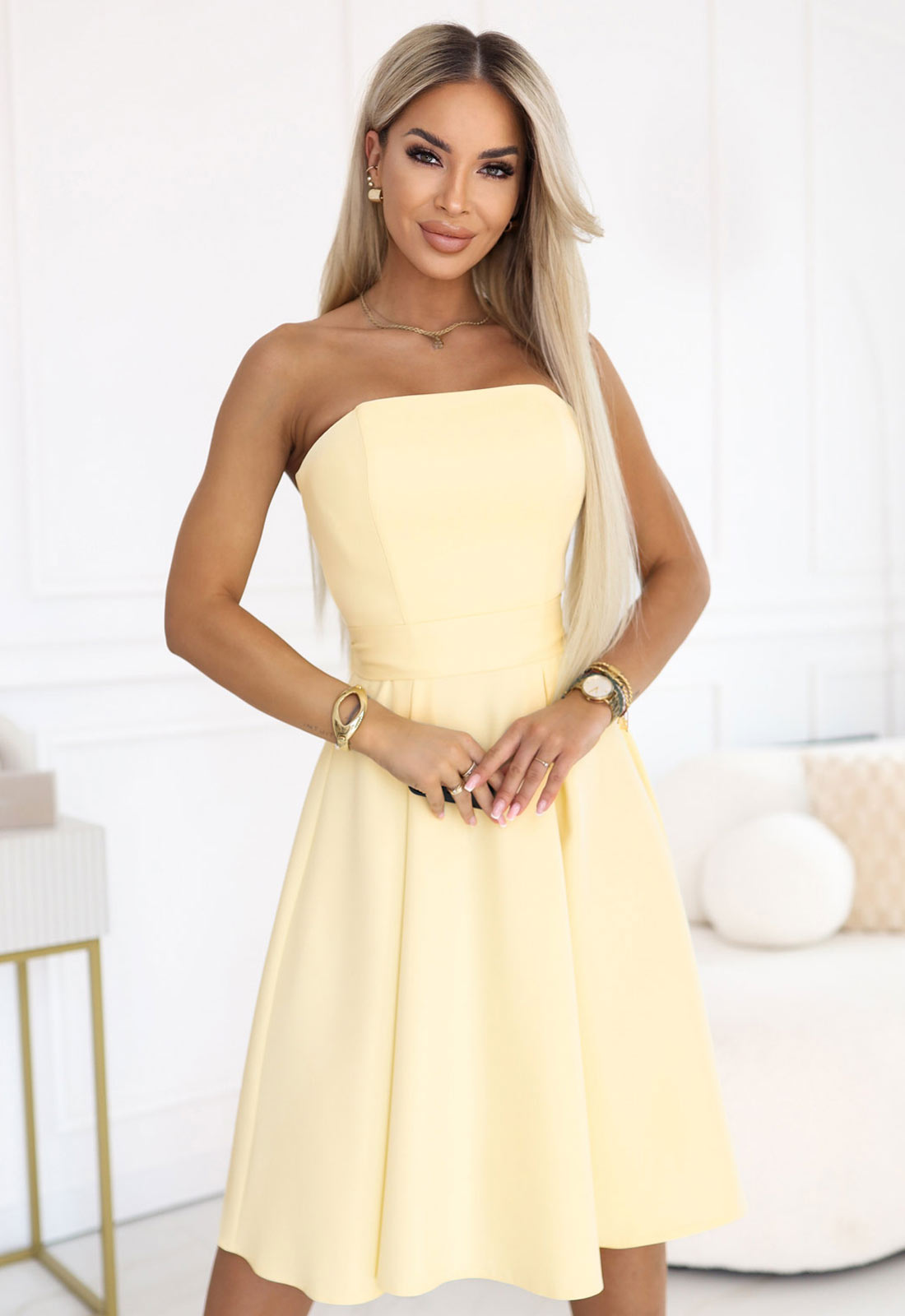 Woman wearing a strapless yellow dress in a bright room