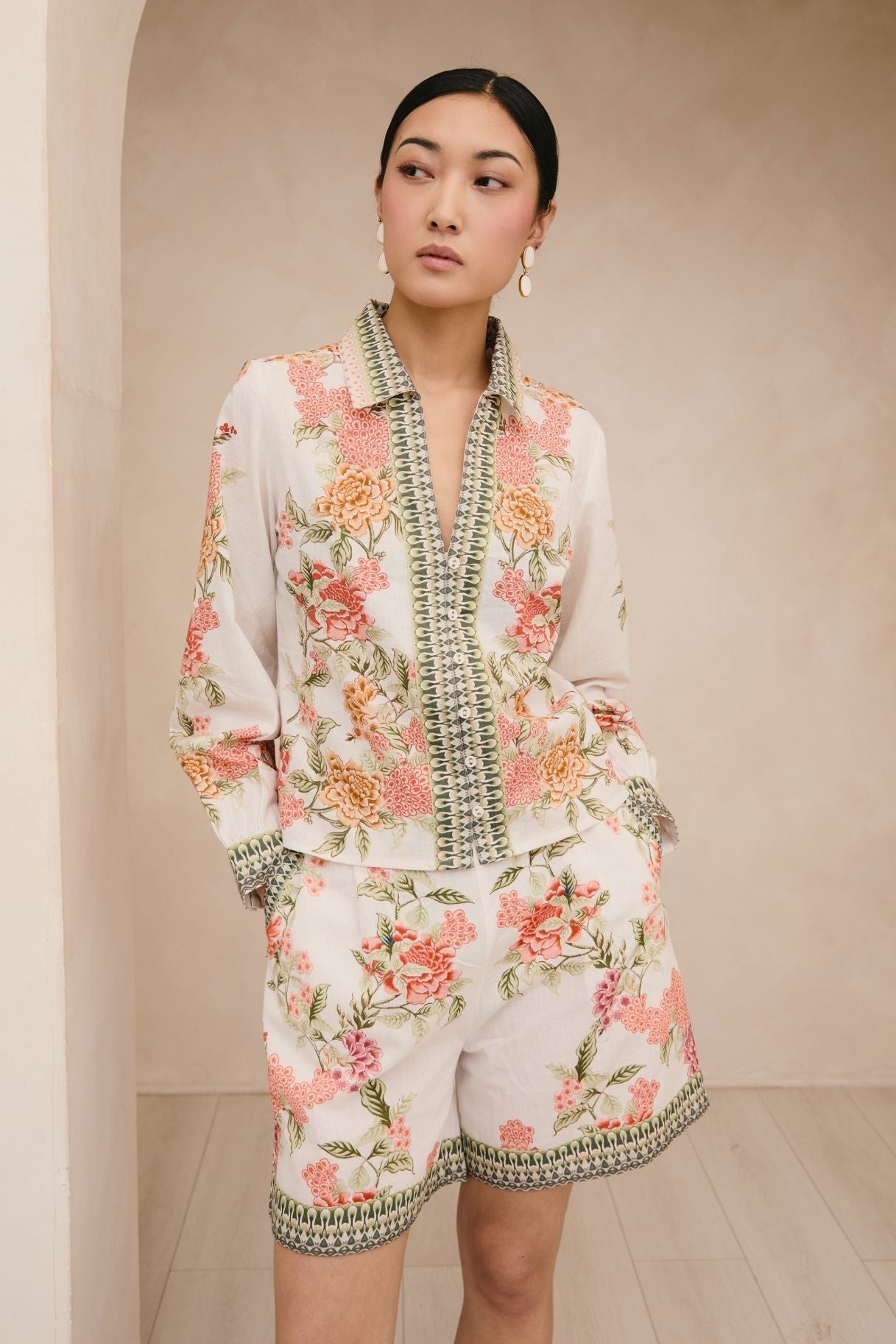 Woman wearing a floral outfit with intricate patterns against a neutral background