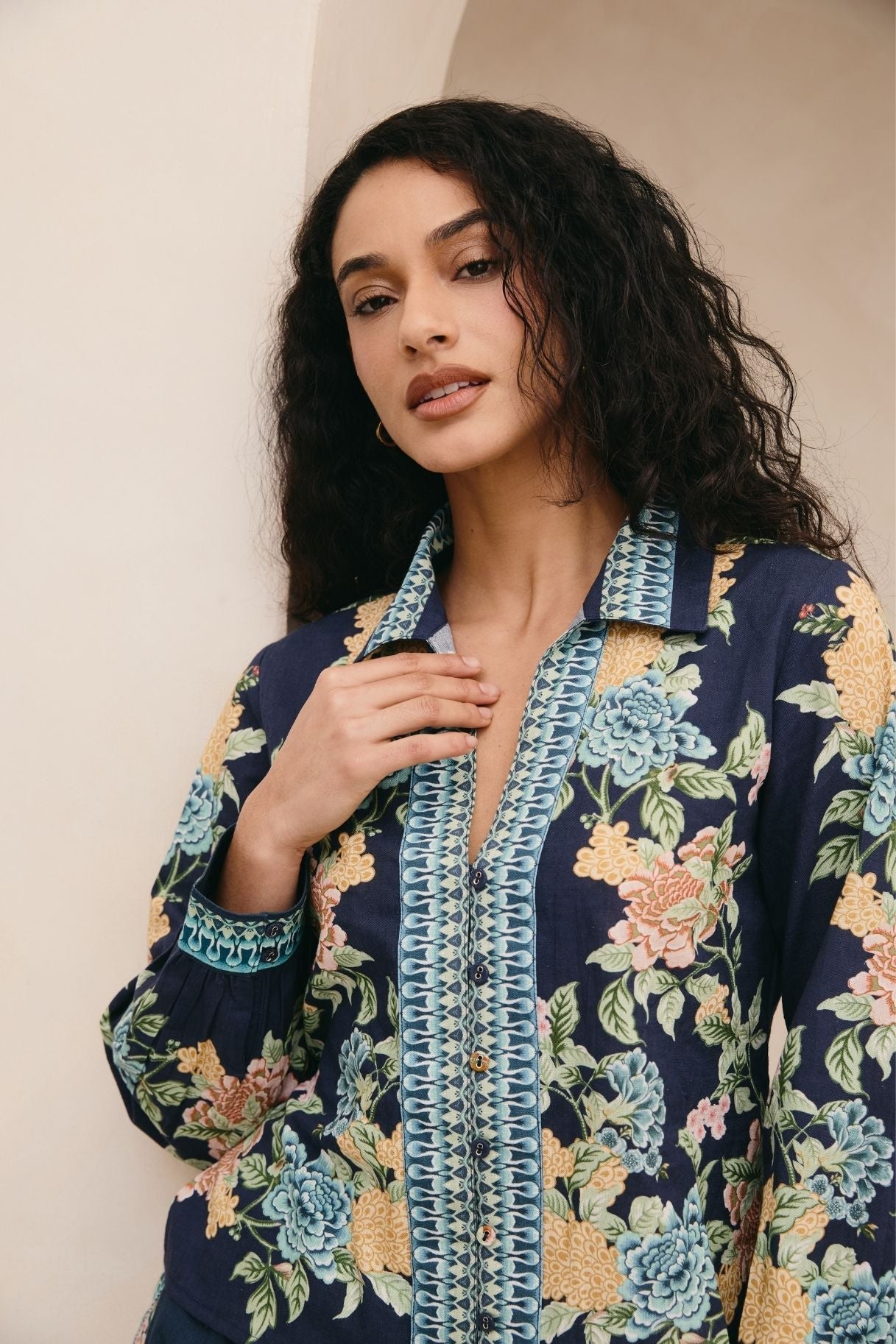 Woman wearing a floral patterned shirt with a neutral background