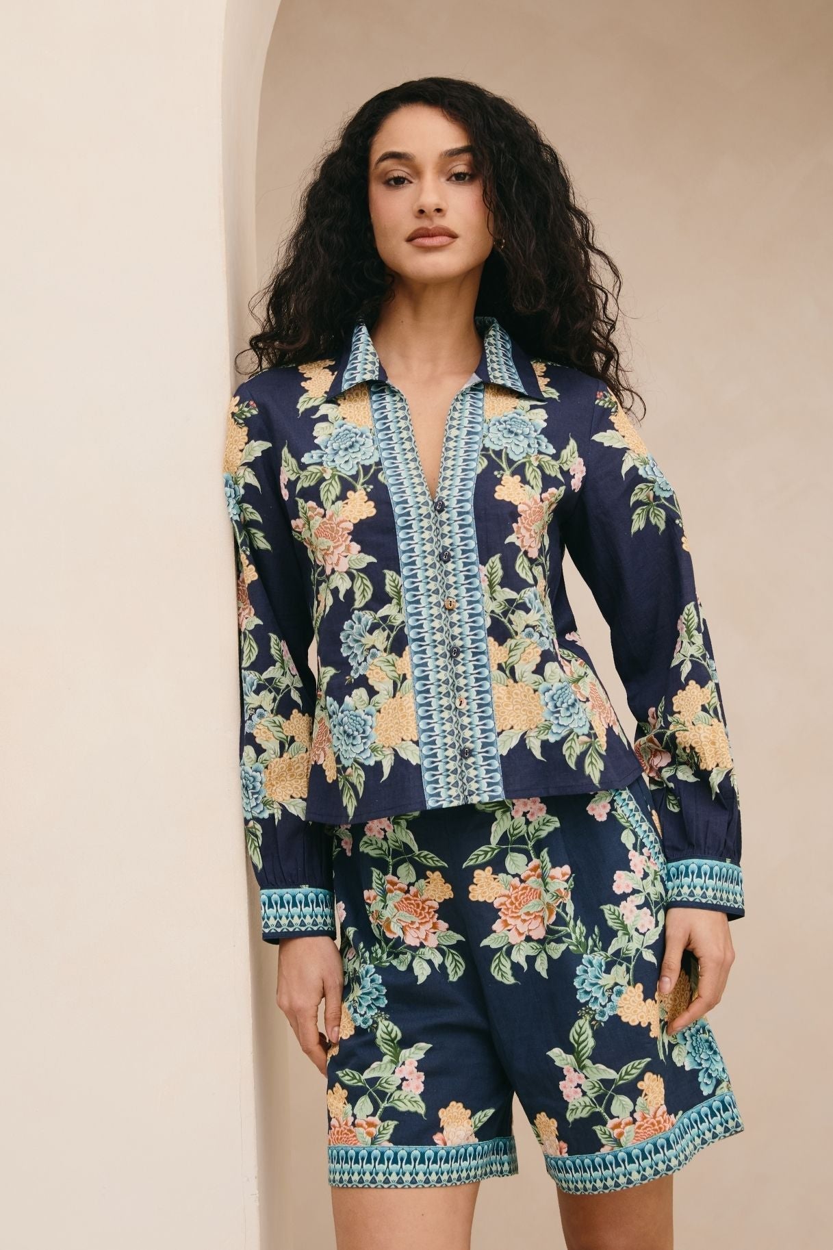 Woman wearing a navy floral outfit against a beige background