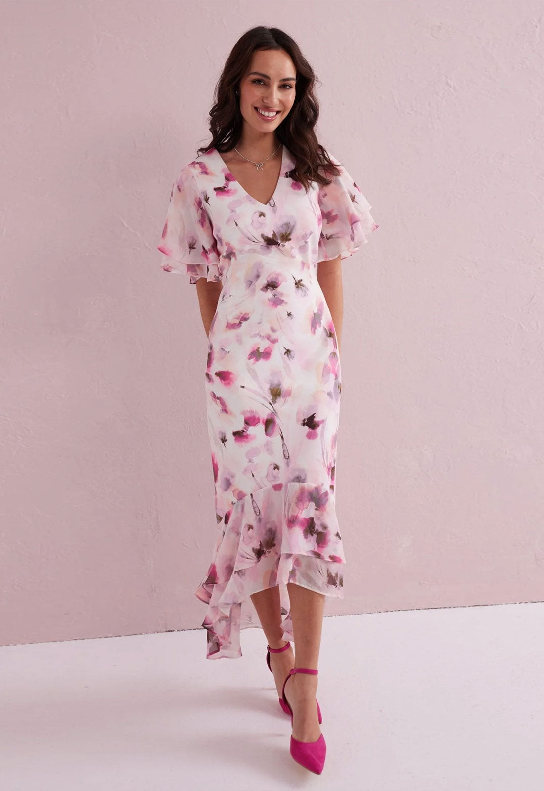 Woman wearing a floral dress against a pink background