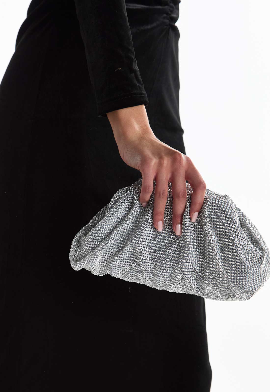Person holding a silver clutch against a black background