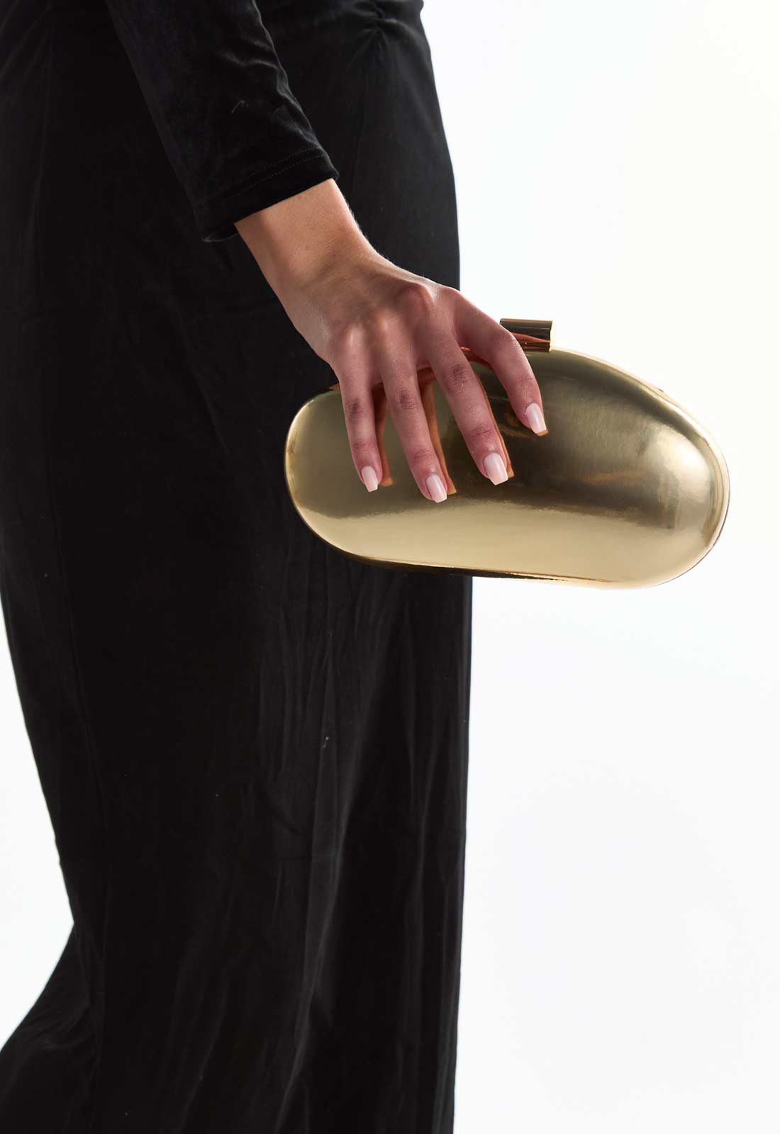Gold clutch held by a person wearing black attire on a white background