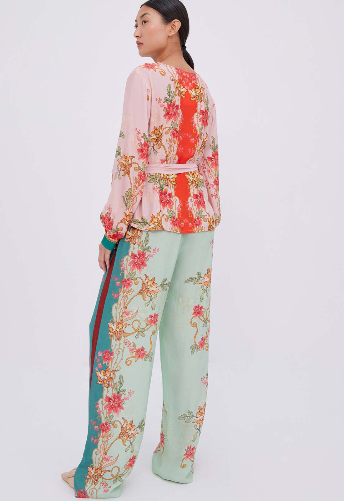 Woman wearing a floral top and pants on a white background