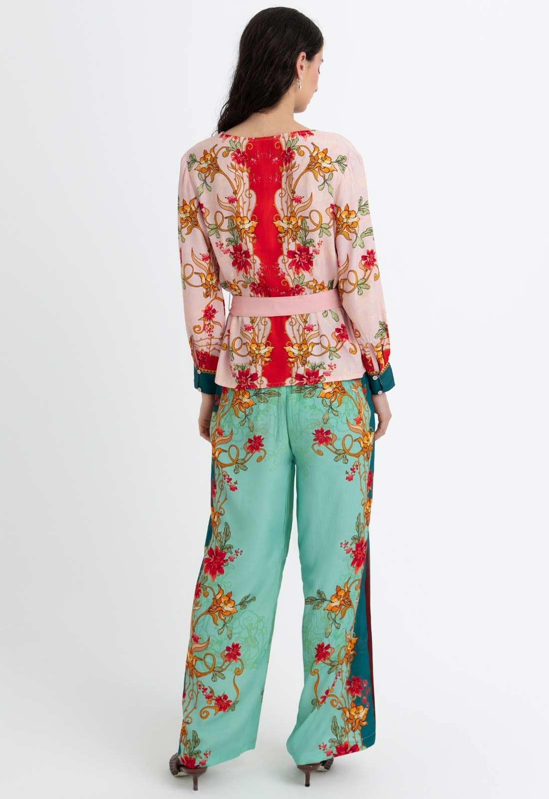 Woman wearing a colorful floral top and pants on a white background