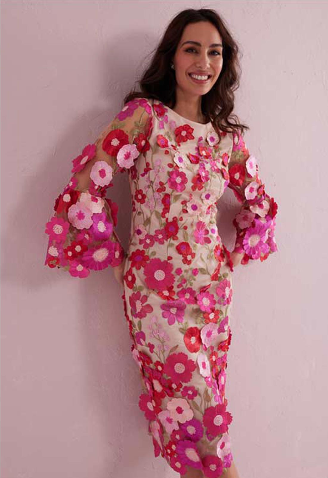 Woman wearing a floral dress with pink and white flowers on a light pink background