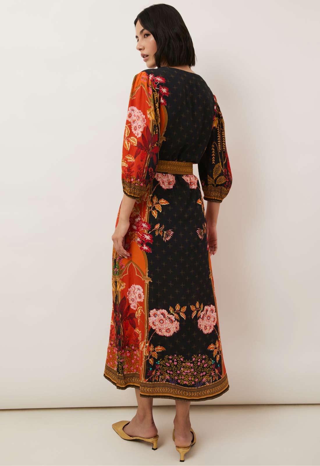 Woman wearing a black dress with colorful floral patterns on a white background