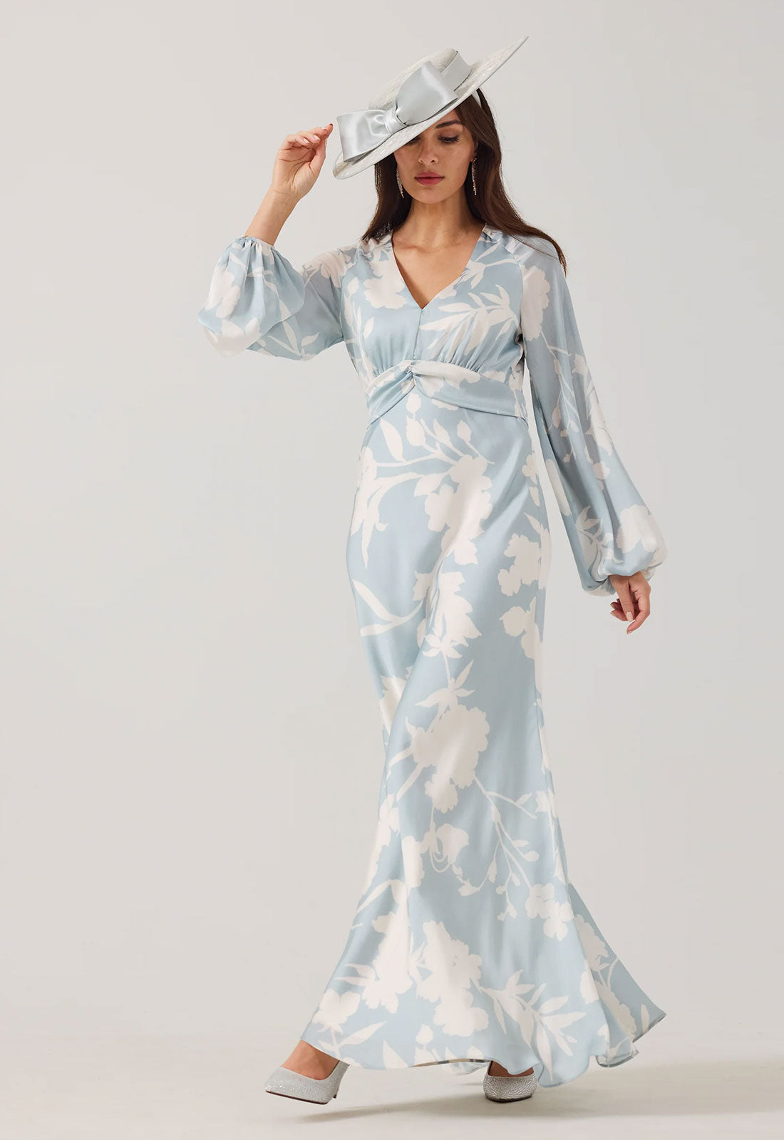 Woman wearing a light blue floral dress with sheer sleeves against a white background