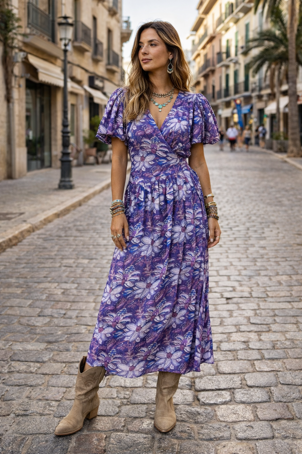 Woman in a purple floral dress standing on a cobblestone street.
