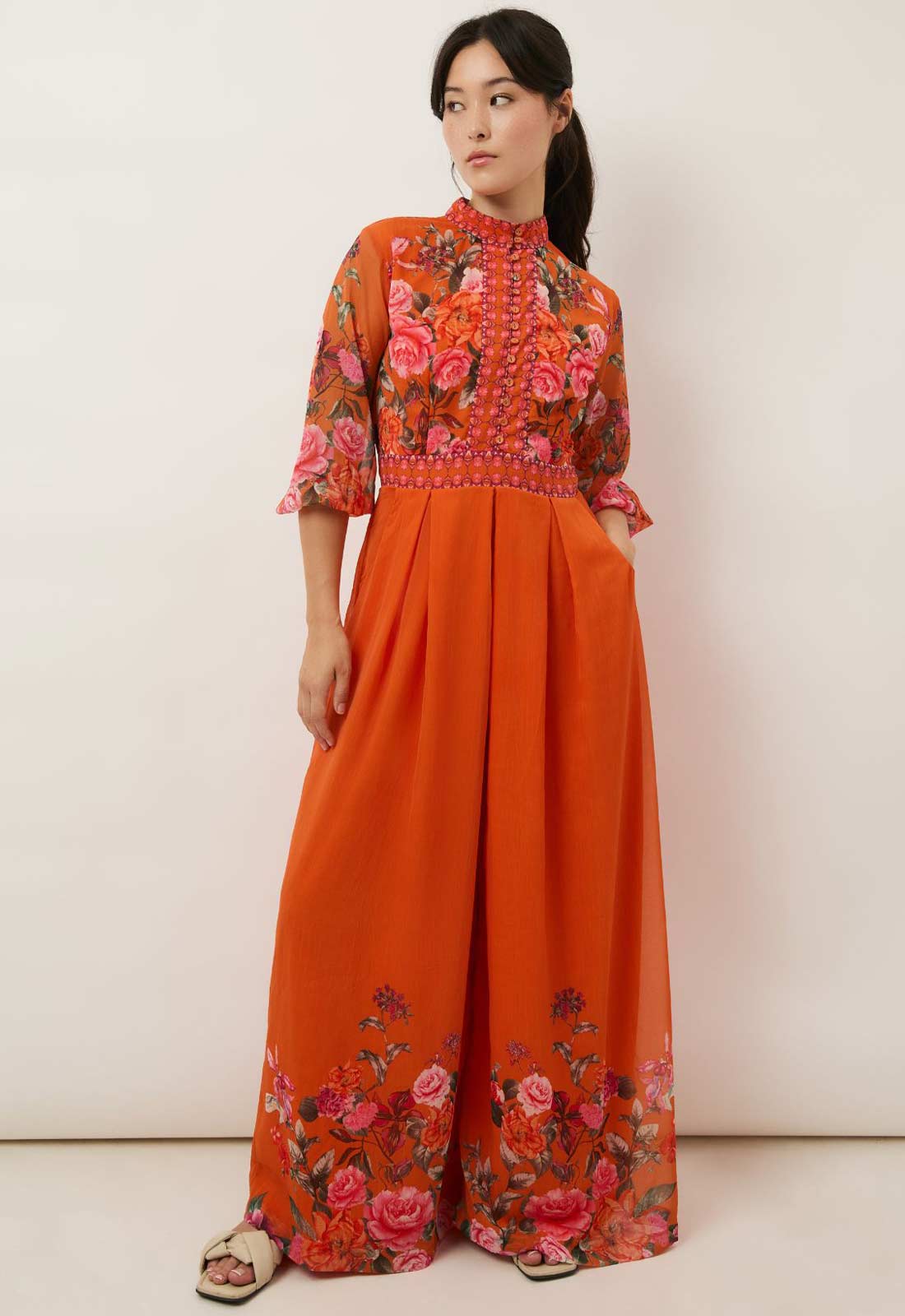 Woman wearing an orange outfit with floral patterns on a white background
