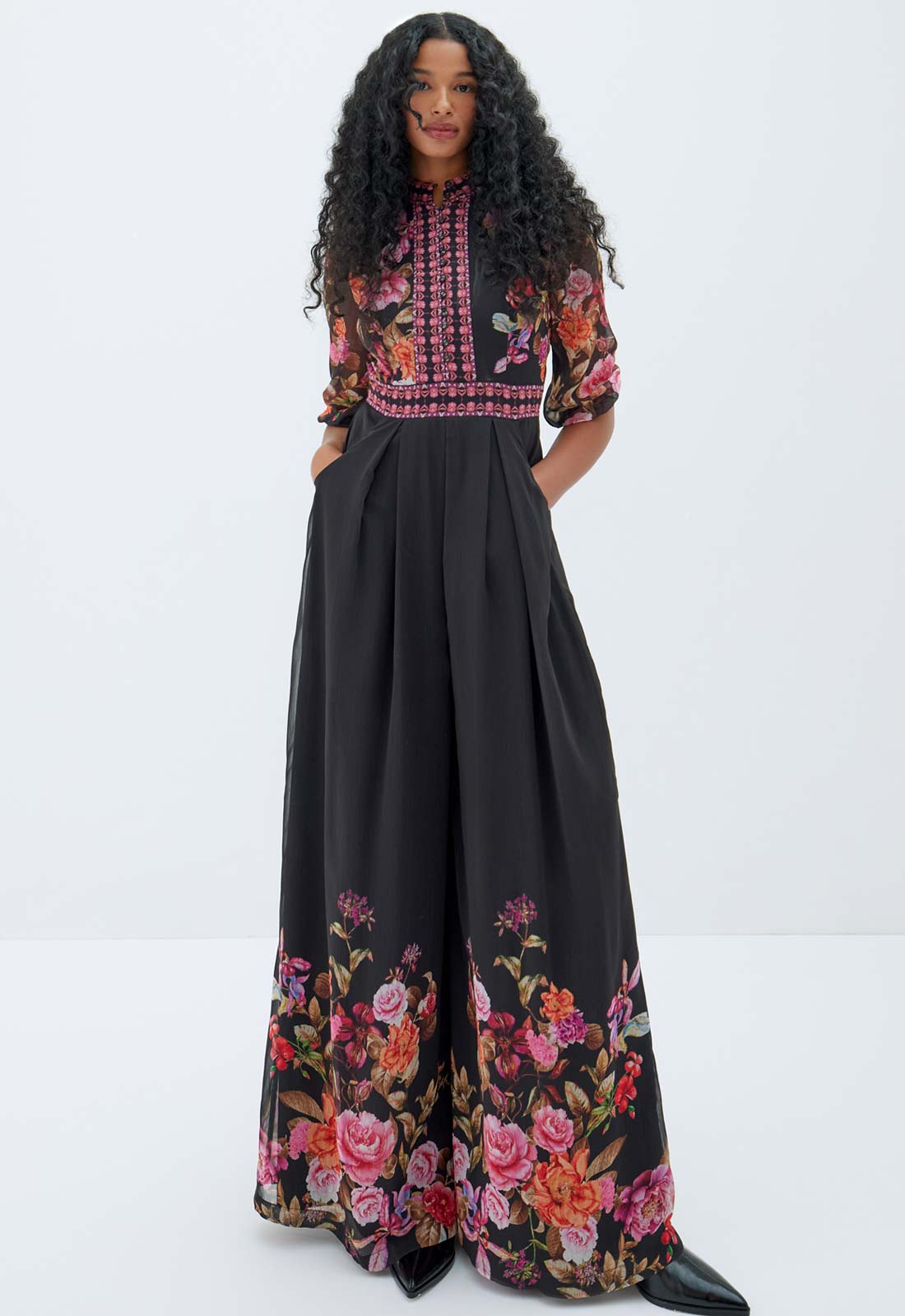 Woman wearing a black outfit with floral embroidery on a white background