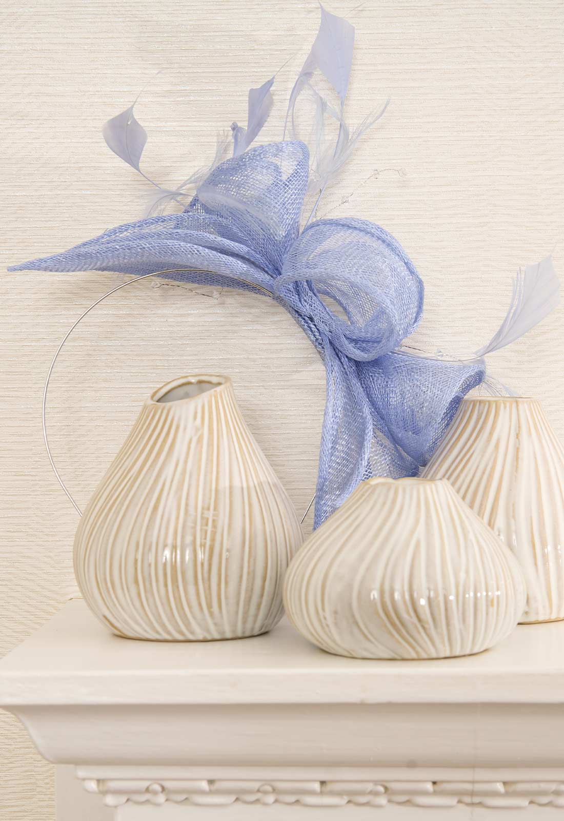 Two decorative shell-shaped vases with a blue ribbon on a light background