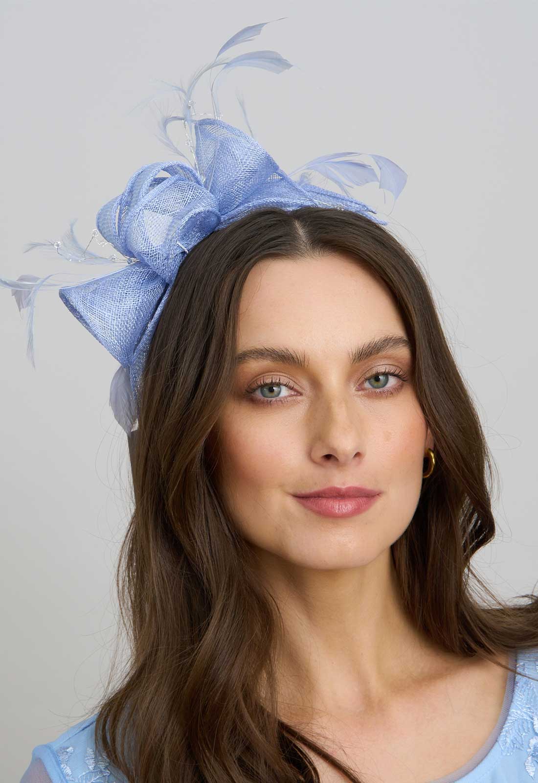 Woman wearing a blue decorative headpiece against a light gray background