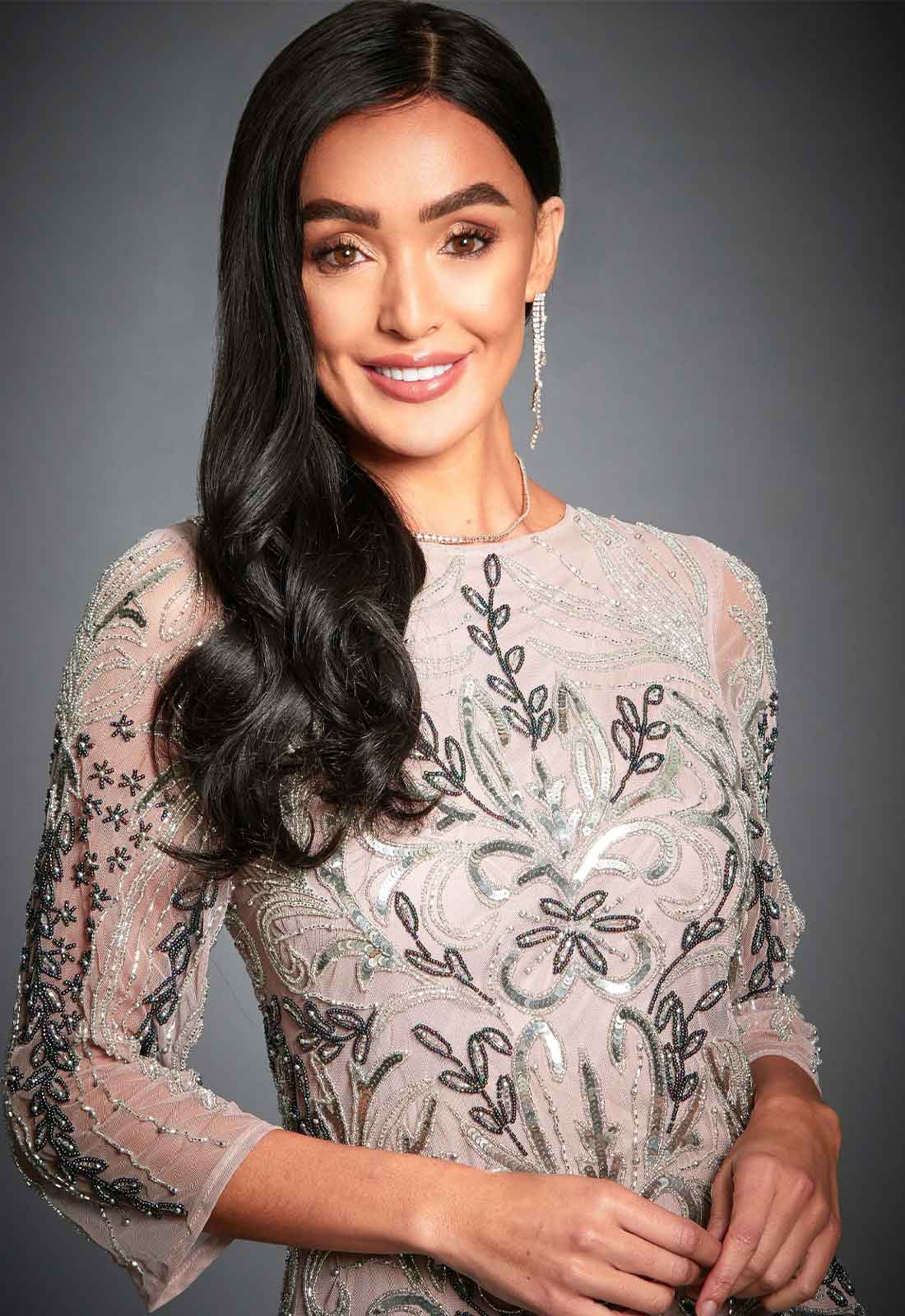 Woman wearing a silver dress with floral patterns against a gray background