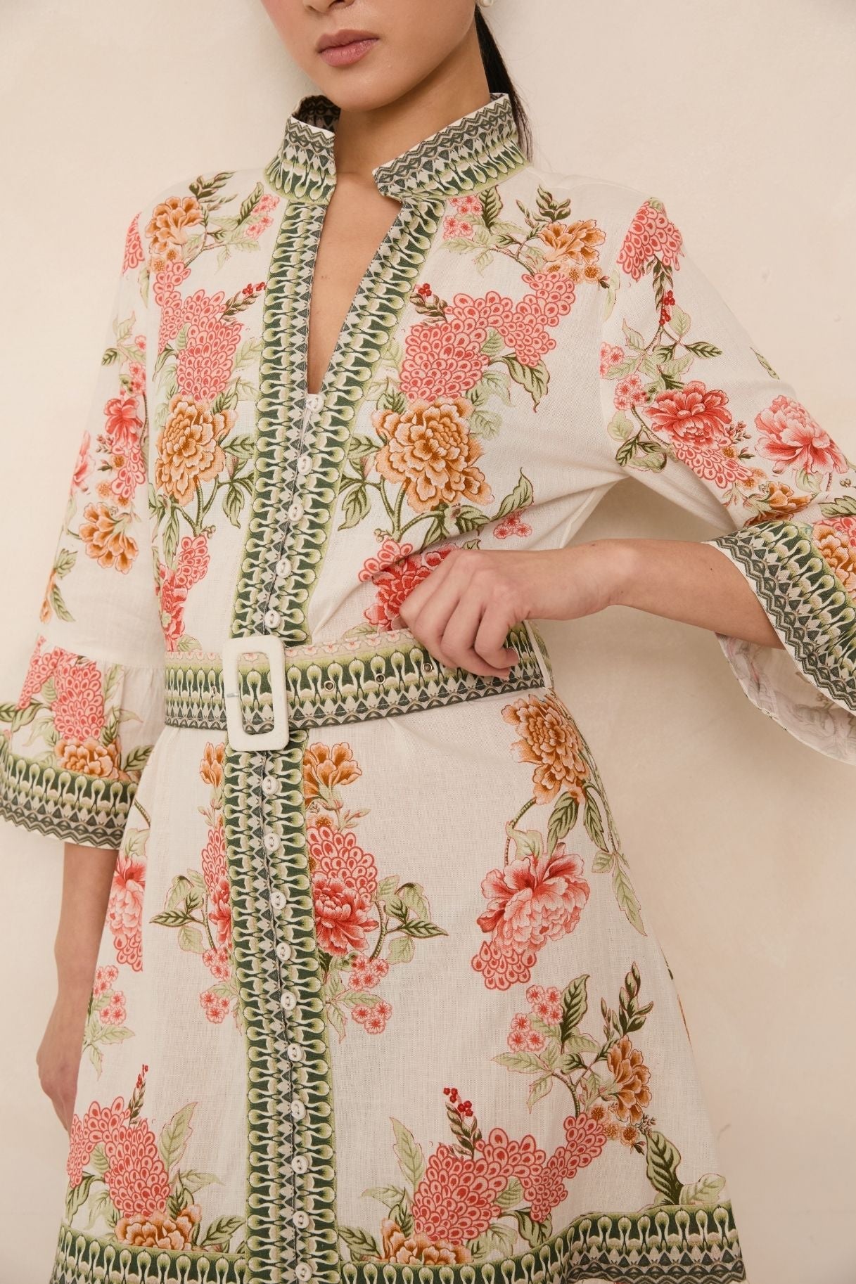 Woman wearing a floral dress with intricate patterns on a plain background