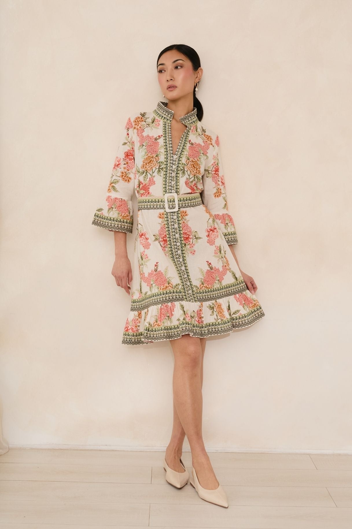 Woman wearing a floral dress with intricate patterns against a plain background