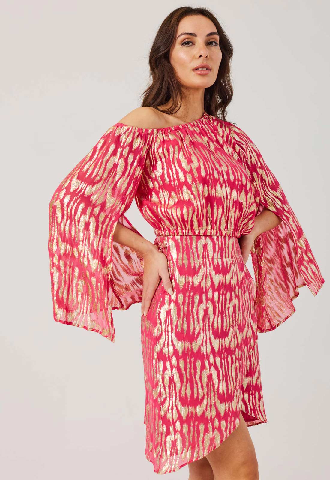 Woman wearing a pink and yellow patterned dress against a white background