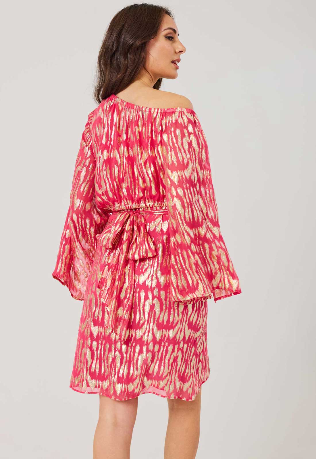 Woman wearing a pink and white patterned dress on a plain background