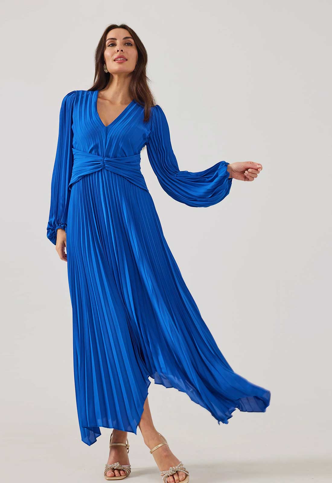 Woman wearing a blue pleated dress against a white background
