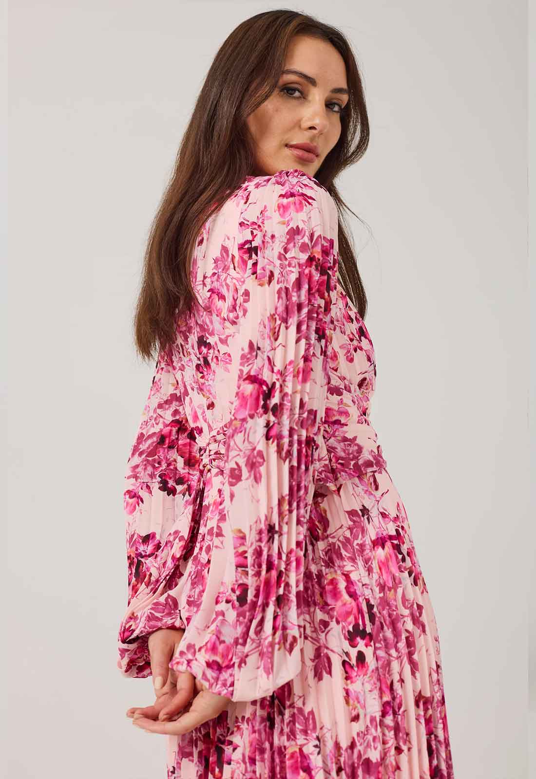 Woman wearing a pink floral dress against a plain background