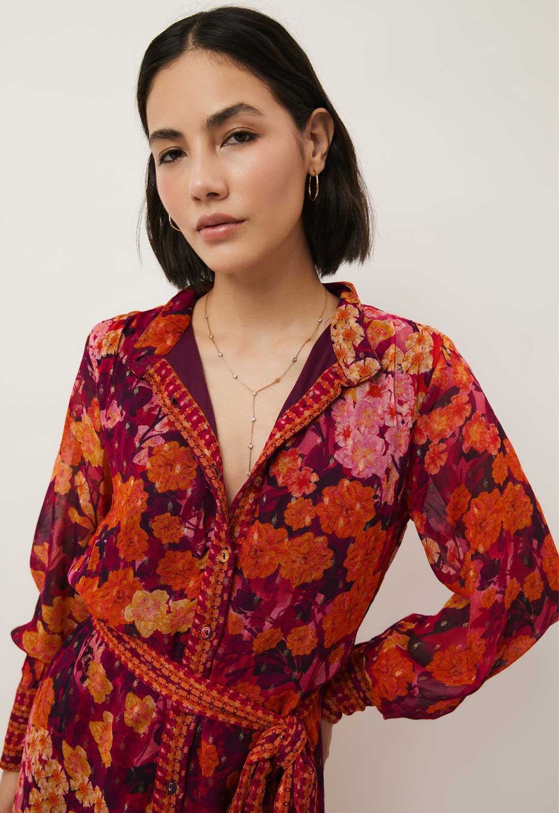 Woman wearing a vibrant floral dress against a plain background