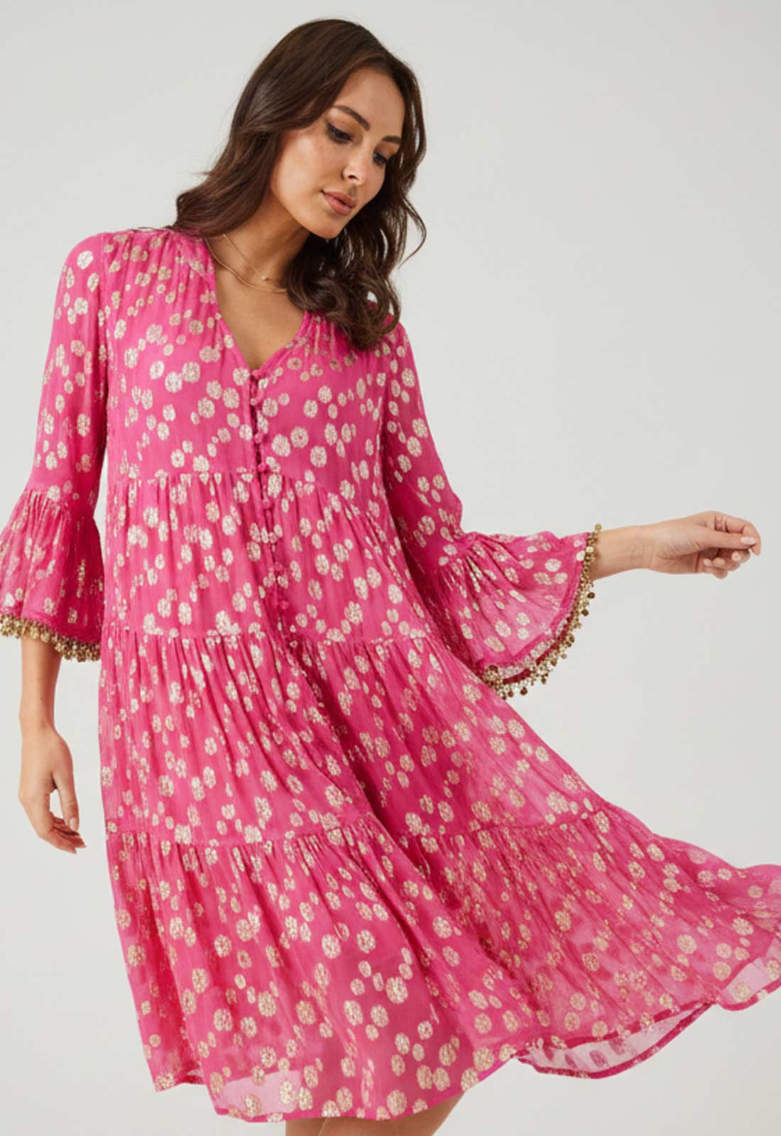 Woman wearing a pink floral dress with gold trim on a white background