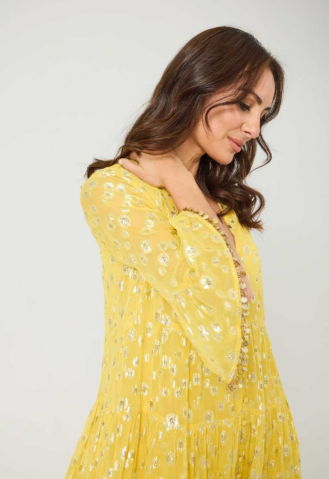 Woman wearing a yellow floral dress against a plain background