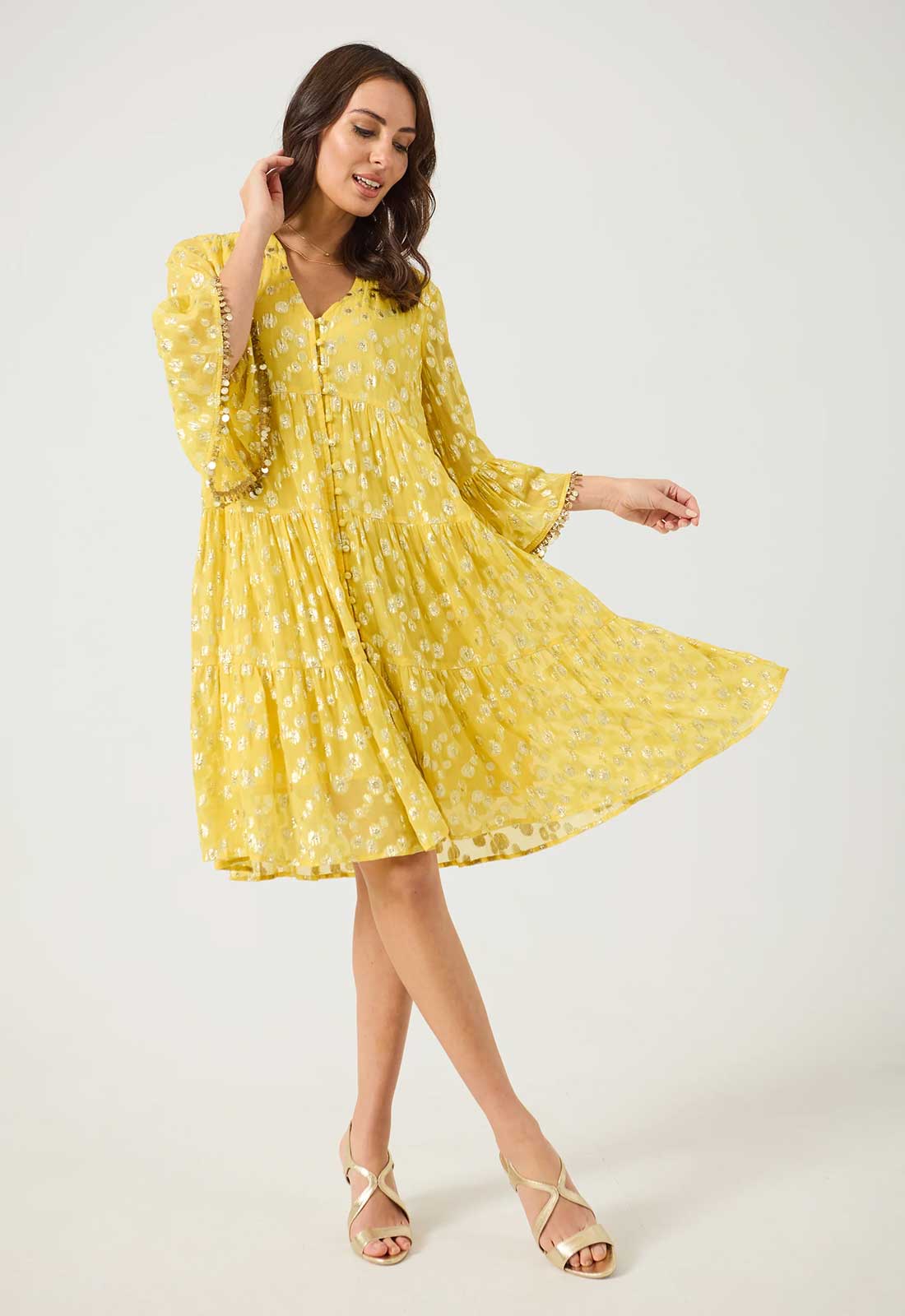 Woman wearing a yellow dress with long sleeves on a white background
