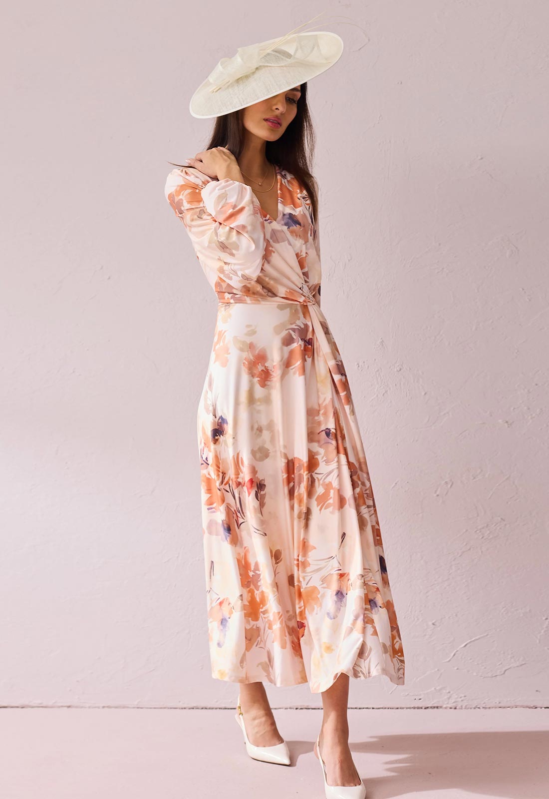 Woman wearing a floral dress and white hat against a plain background