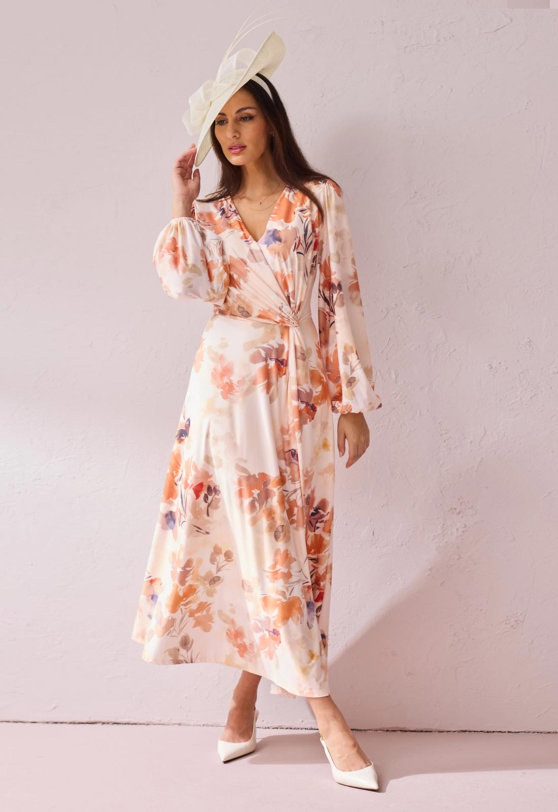Woman wearing a floral dress and white hat against a plain background