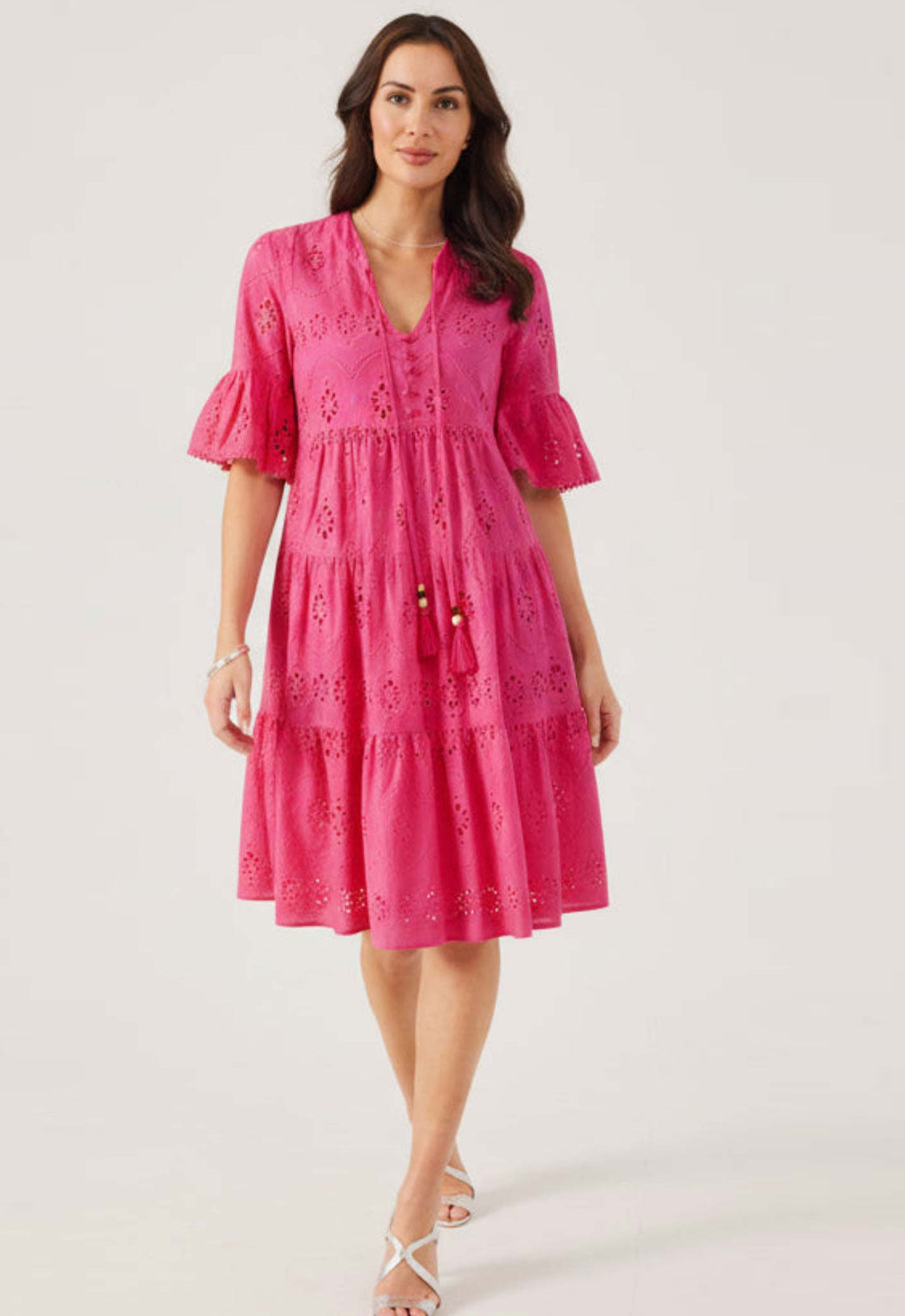 Woman wearing a pink dress with lace details on a white background