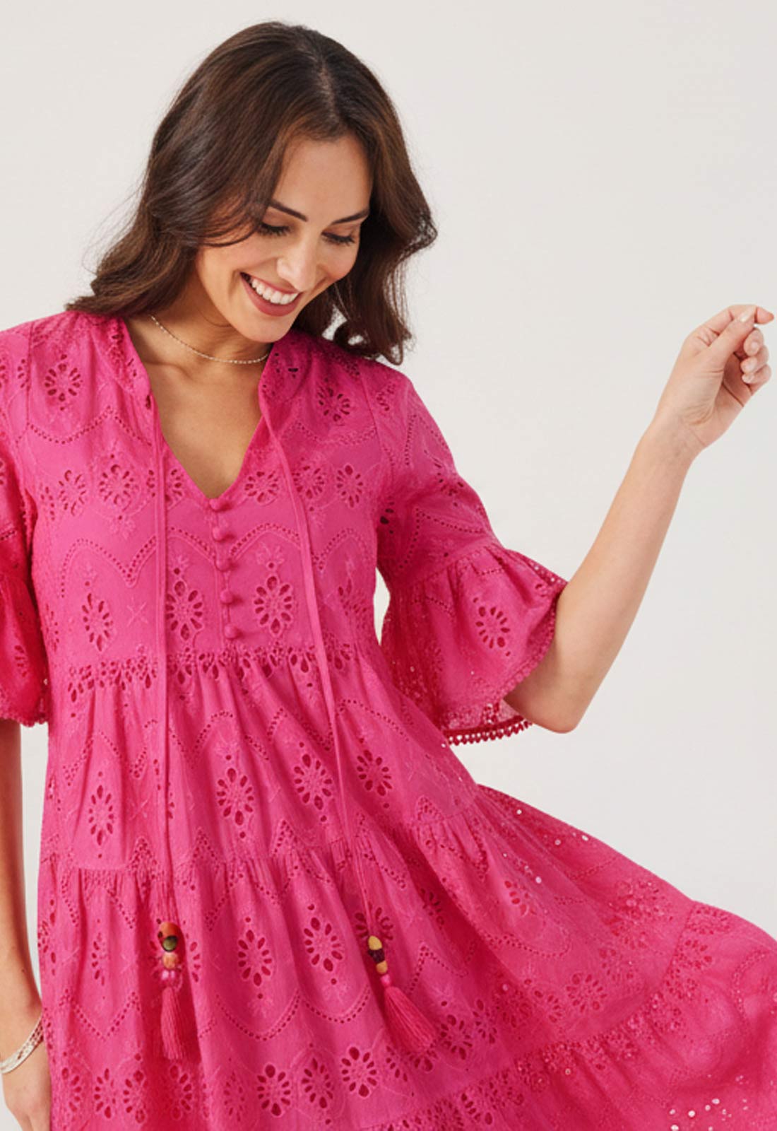 Woman wearing a pink dress with intricate patterns on a white background