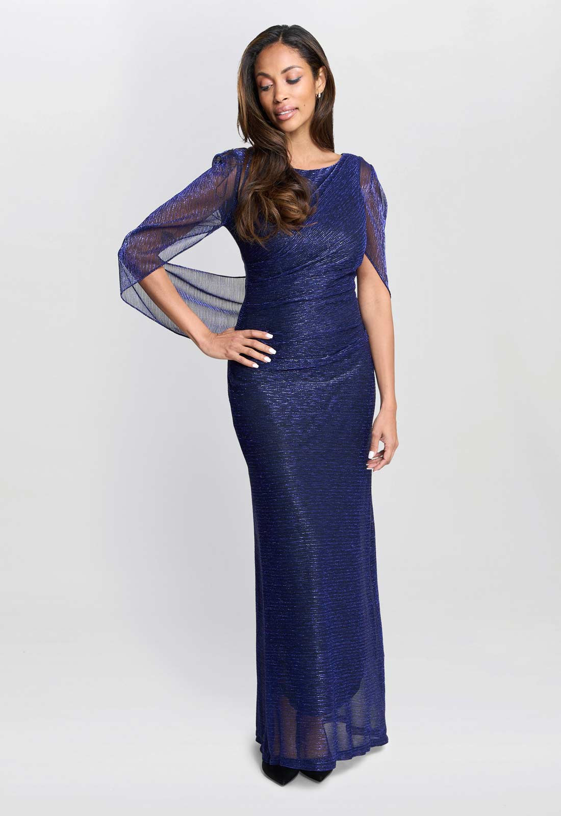 Woman wearing a blue evening gown with sheer sleeves on a white background