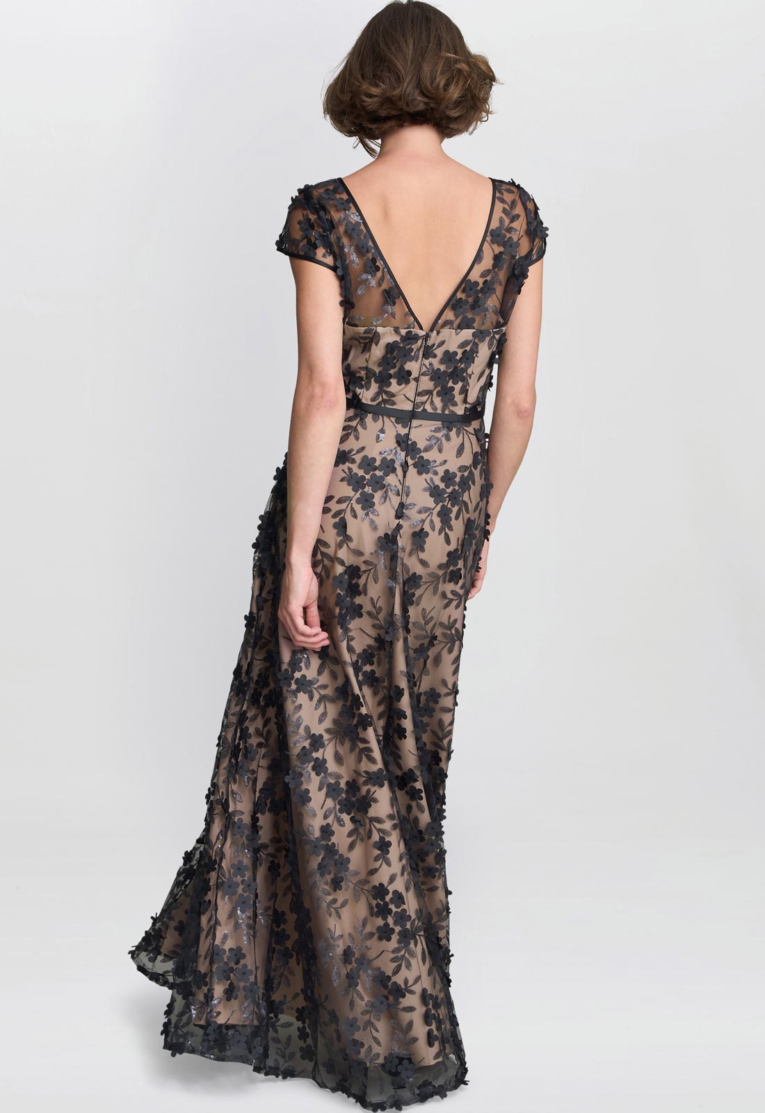 Woman wearing a floral lace dress on a plain background