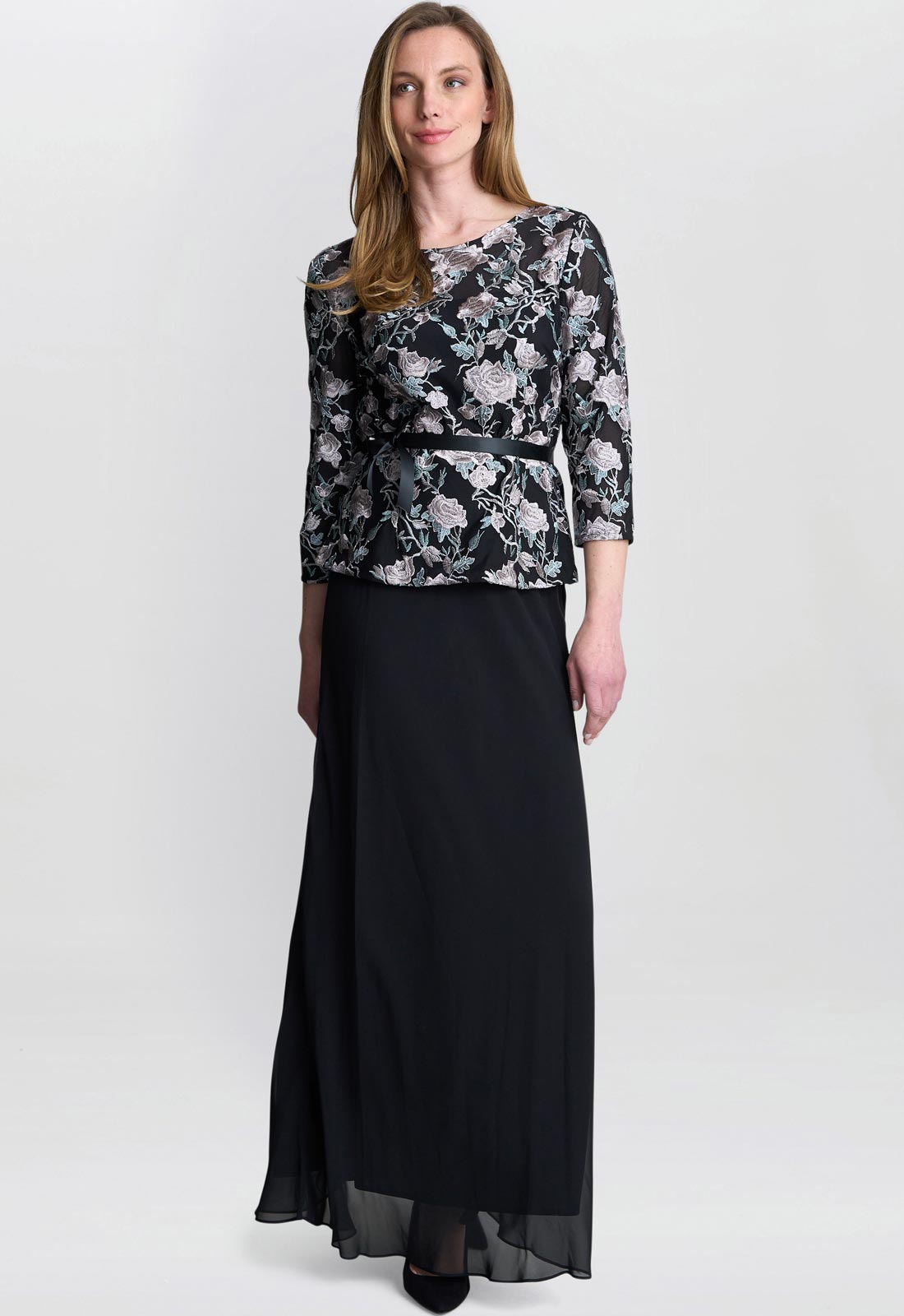 Woman wearing a floral top and black skirt on a white background