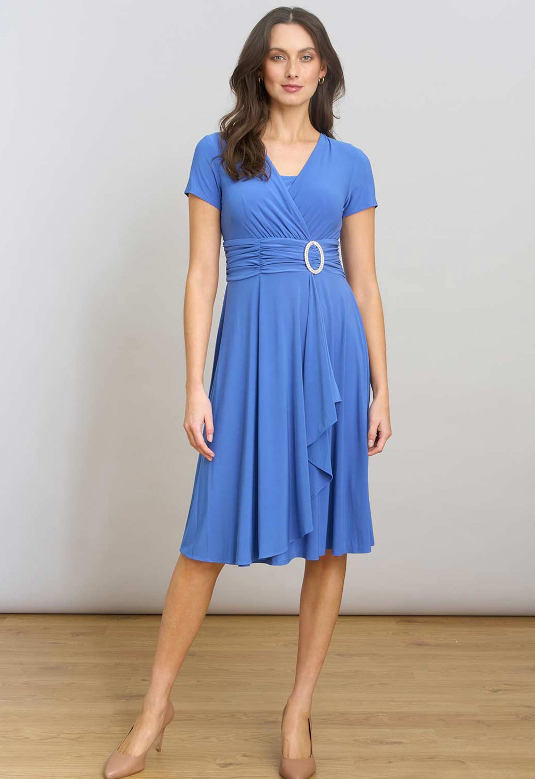 Woman wearing a blue dress with a belt against a plain background