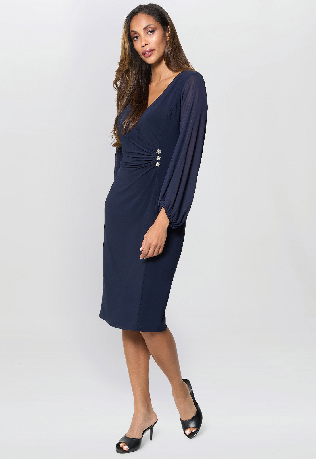 Woman wearing a navy blue dress with wide sleeves on a white background